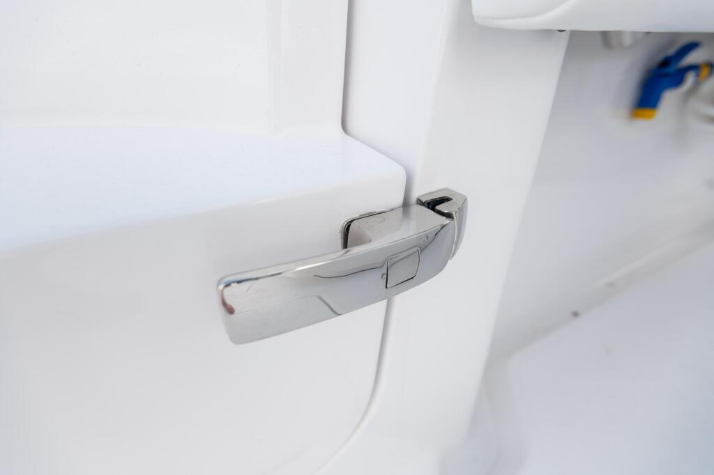 Chrome door handle on white interior cabin door of a boat