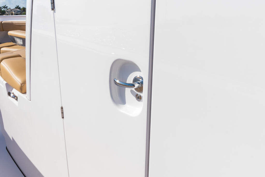 Chrome handle on white cabin door with tan seating visible through window