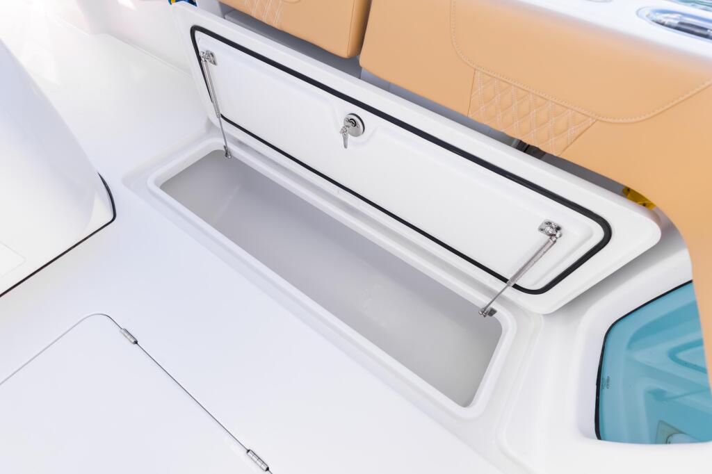 Open in-deck fish box with white interior and chrome hardware, showing storage compartment on boat