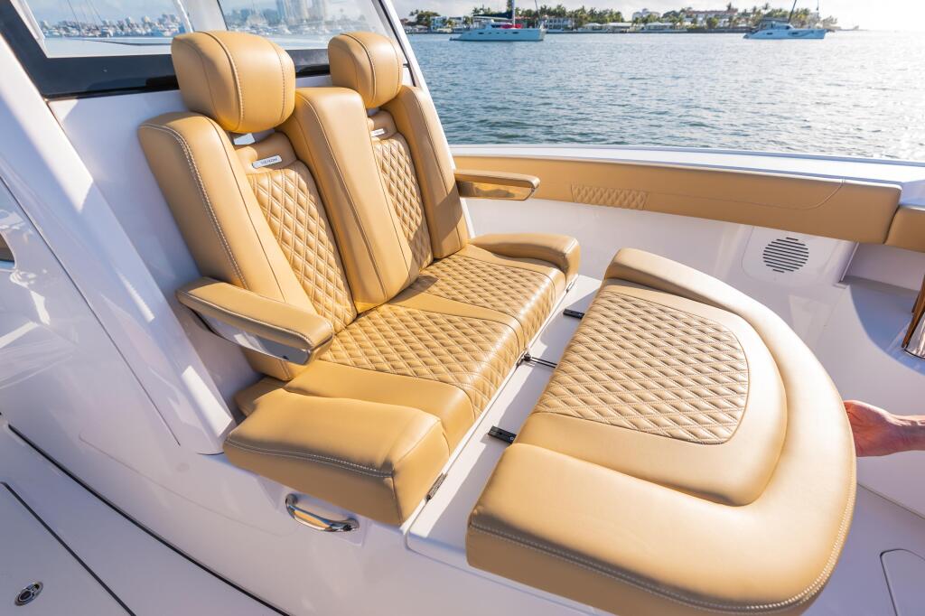 Tan leather captain and passenger seating with quilted pattern inside boat cabin facing water and marina