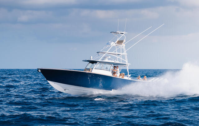 Blue and white sport fishing boat cruising offshore with passengers aboard in open ocean