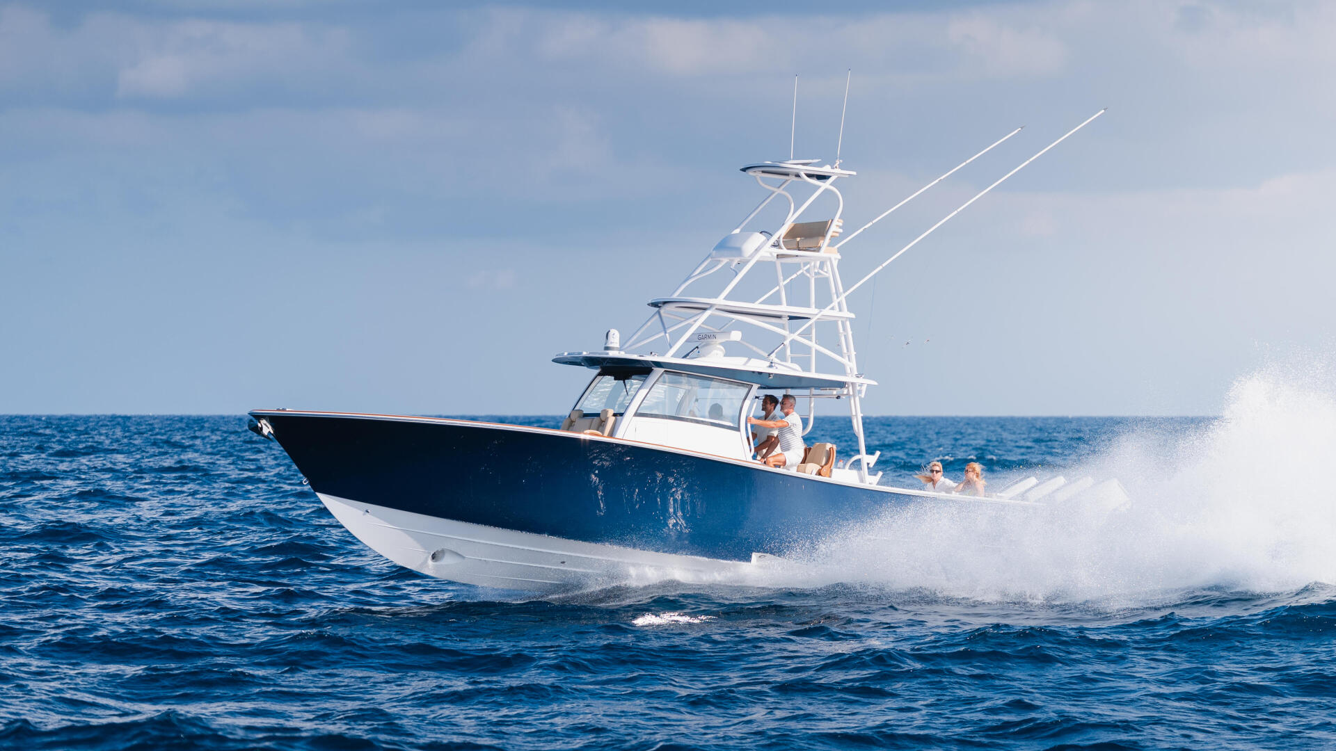 Blue and white sport fishing boat cruising offshore with passengers aboard in open ocean