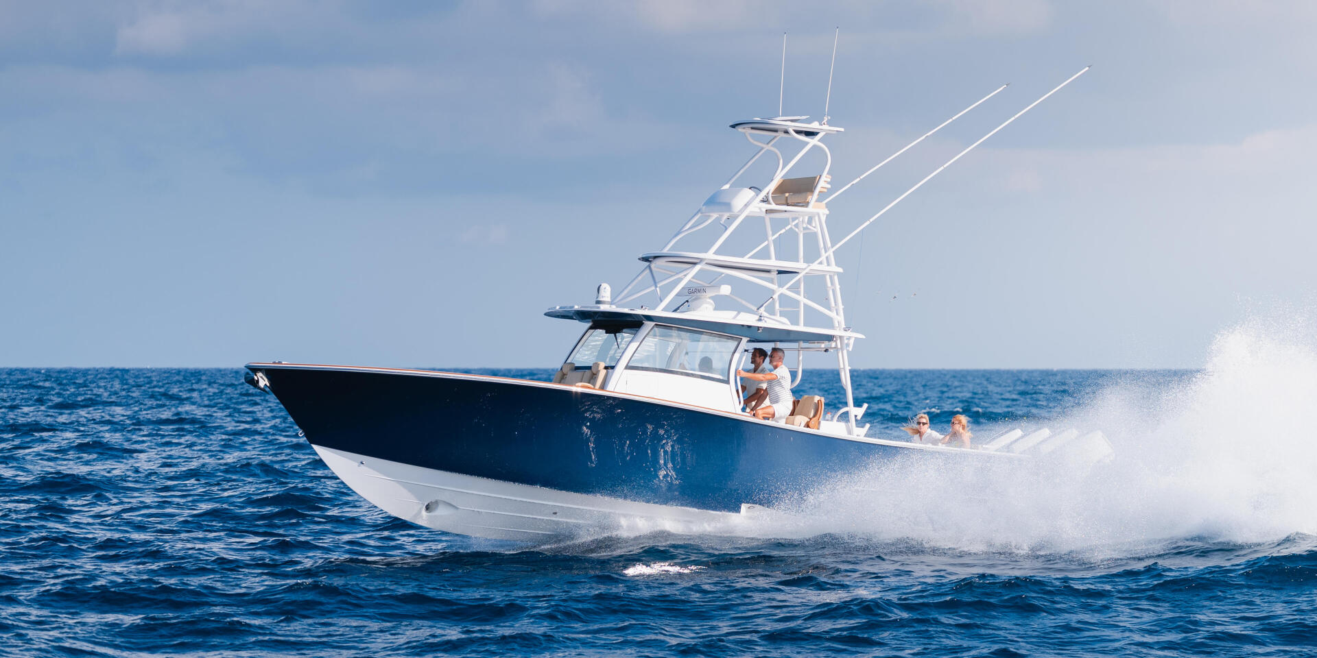 Blue and white sport fishing boat cruising offshore with passengers aboard in open ocean