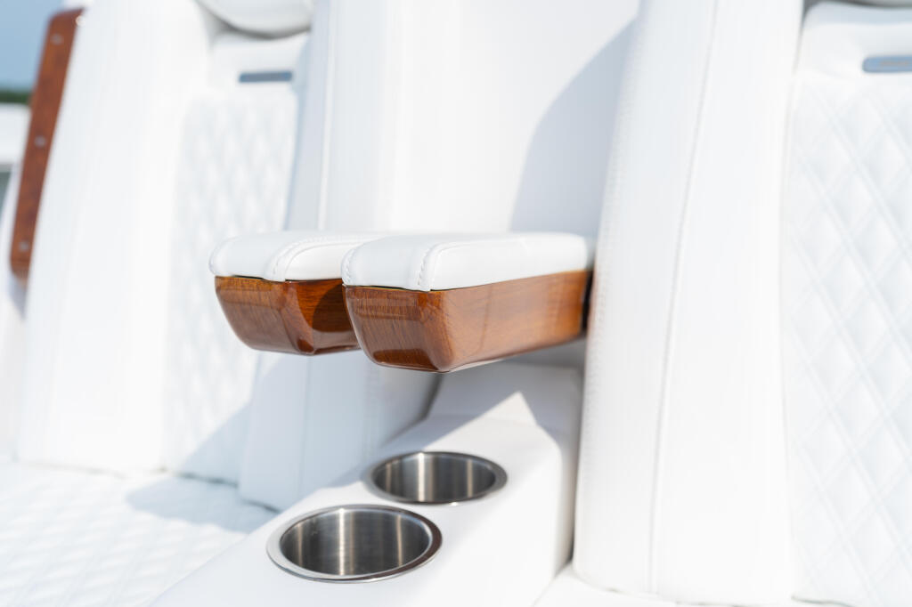 Faux-teak armrests with white cushioning and stainless steel cup holders on boat interior