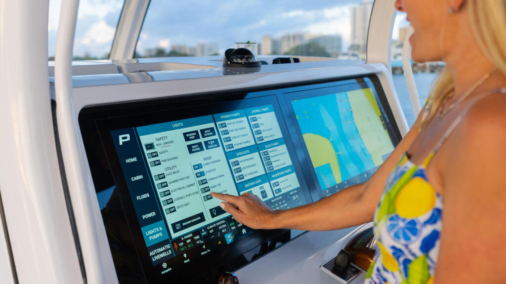 Woman at helm operating touchscreen display with multiple menu options overlooking waterfront cityscape
