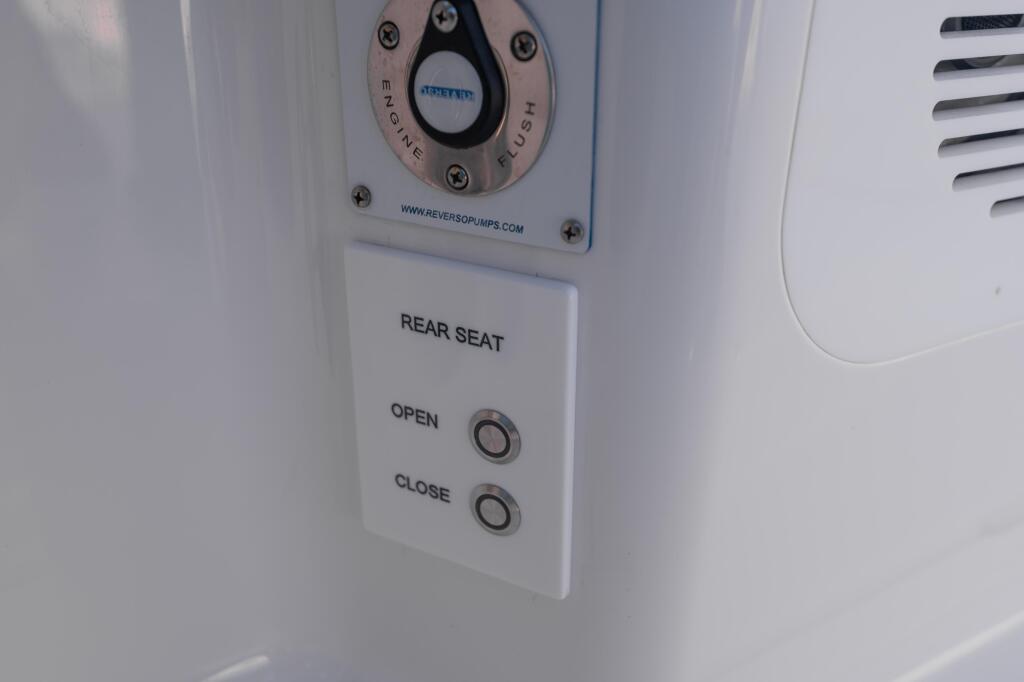 Engine control dial and rear seat open/close buttons mounted on white boat interior panel