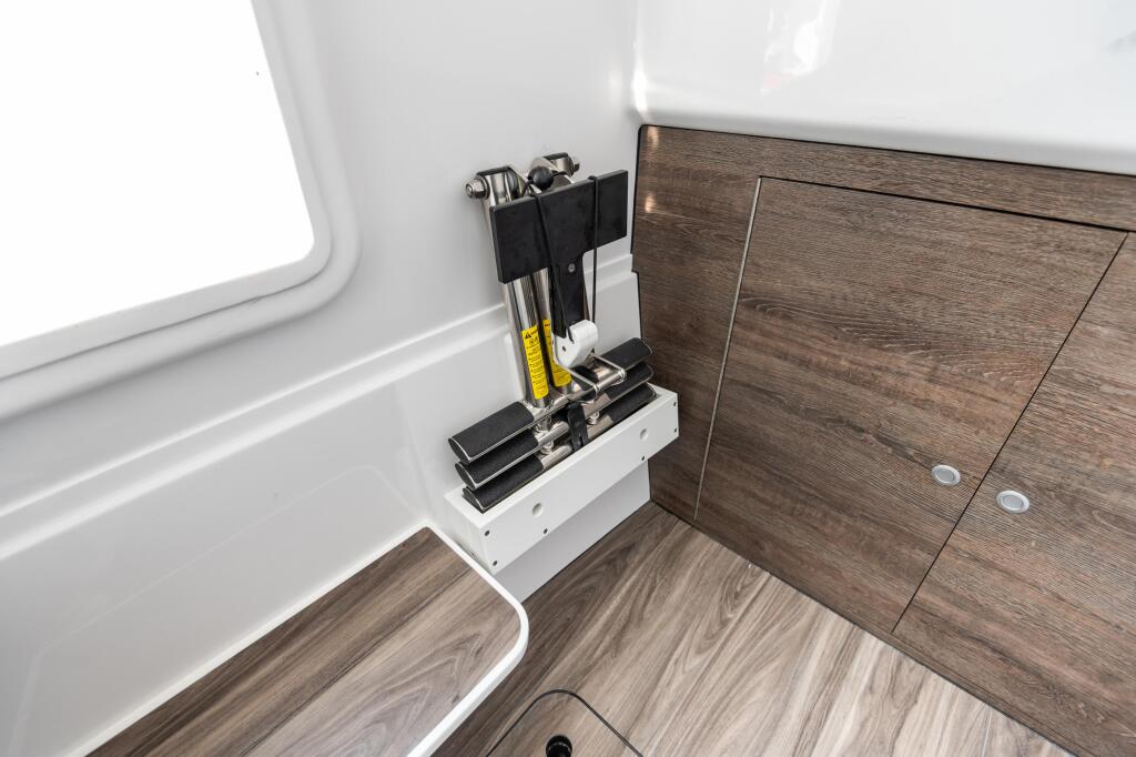 Organized fishing tool storage rack mounted inside boat cabin with white walls and wood cabinetry