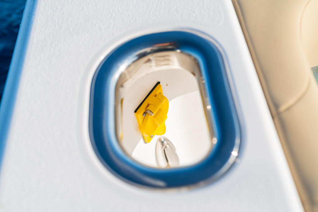 Bright yellow cleat secured on white boat exterior with blue trim around circular opening