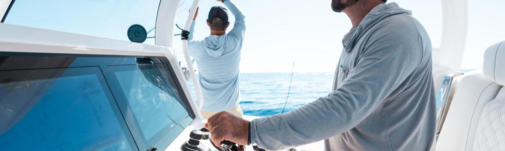 Boater at the helm with another person on deck during an offshore fishing trip