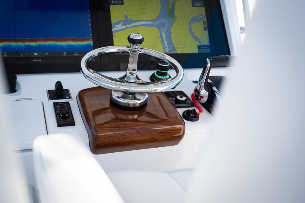 Helm station with polished stainless steel wheel on faux-teak base, GPS display, and control panels