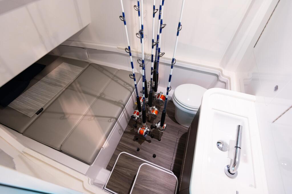 Boat cabin interior with multiple fishing rods stored vertically in rod holders above a cabin berth and head