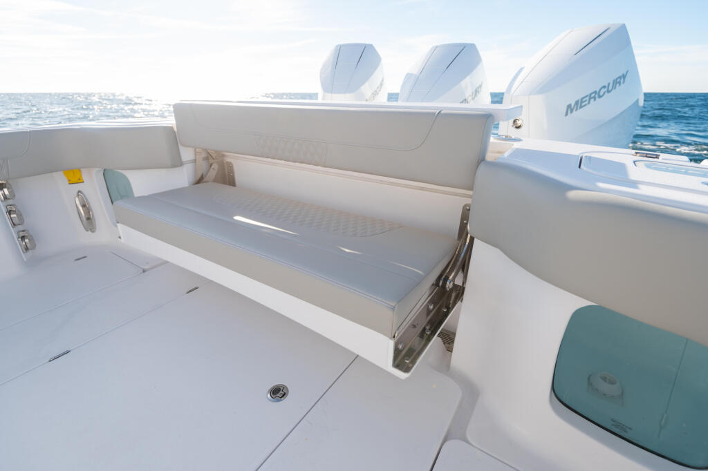 Flip-down bench seat with backrest in boat cockpit, Mercury outboard engines visible behind