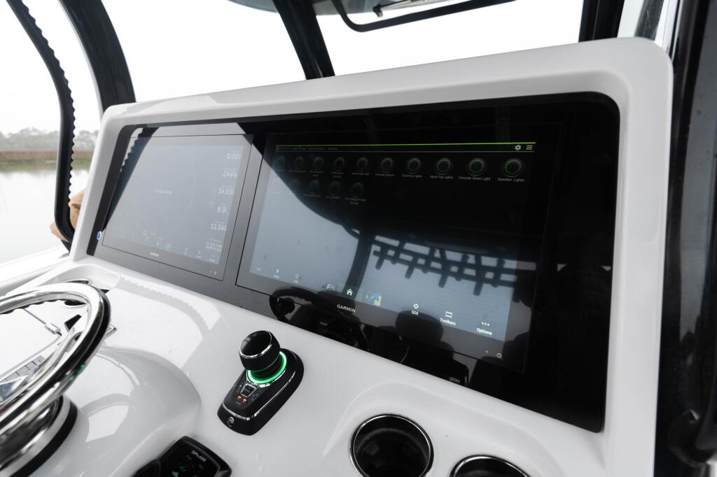 Helm console with dual displays, joystick control, and integrated lighting system in white boat interior