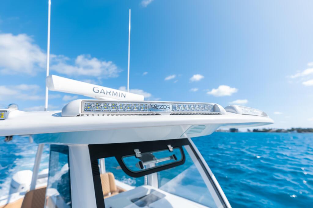 Garmin electronics and antenna mounted on hardtop of center console boat with calm blue water in background