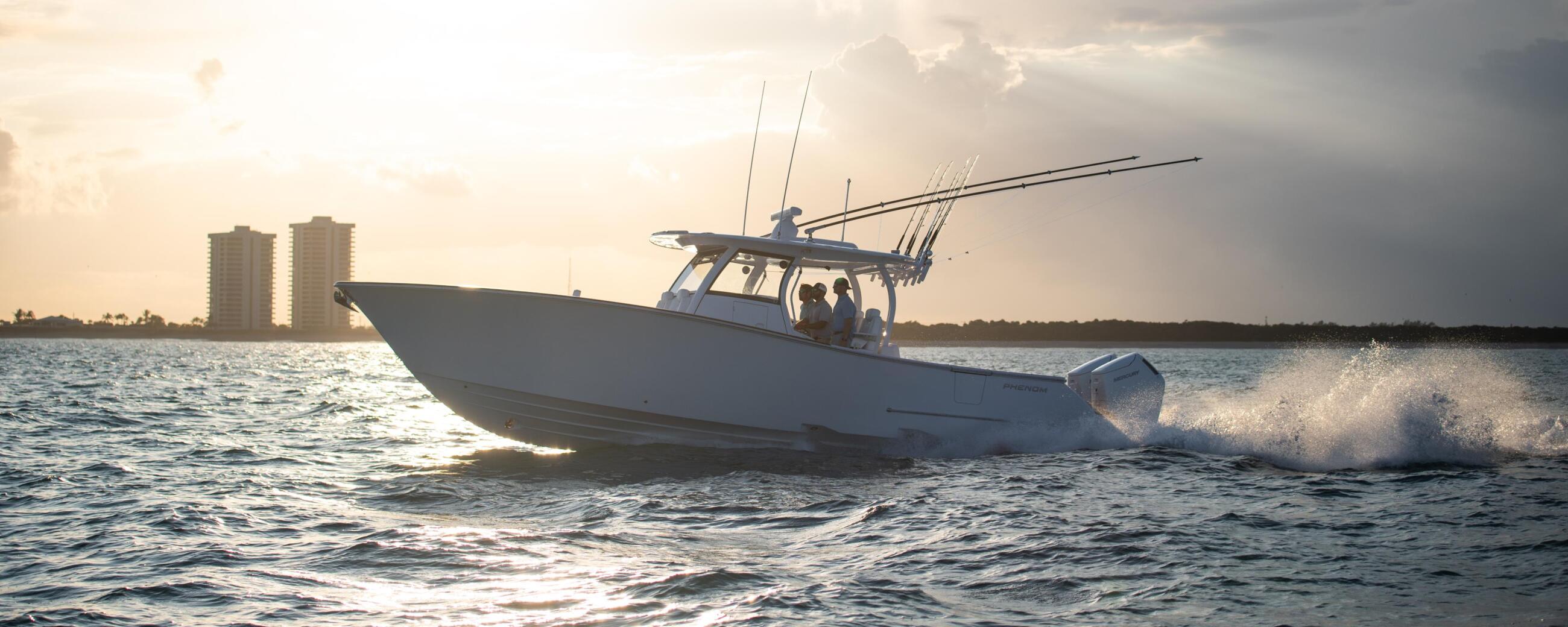 White center console fishing boat running through offshore waves at sunset with coastal buildings in the background