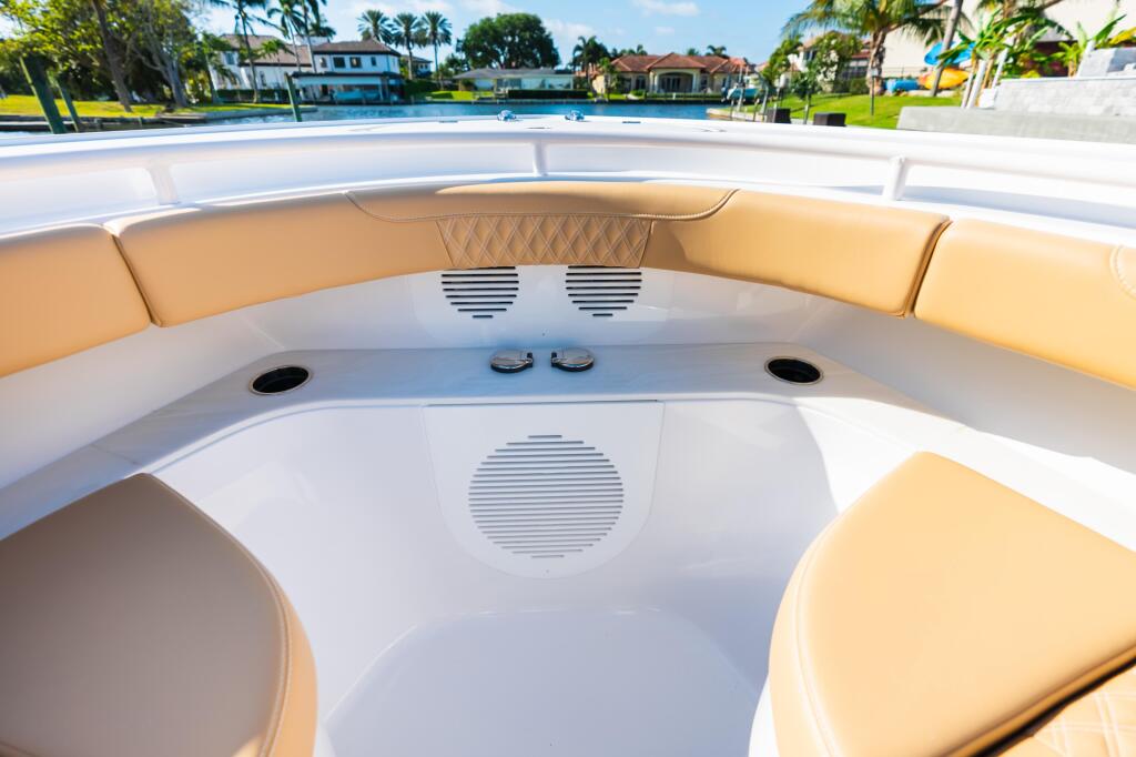 Luxury boat cabin with tan leather seating, white finishes, and audio speakers overlooking a waterfront residential community