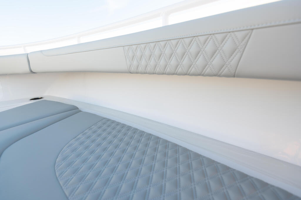 Quilted white upholstered seating and storage compartments in a boat cabin interior