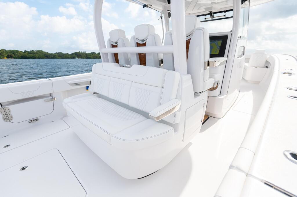 White fiberglass center console with cushioned seating and hard-top canopy overlooking calm water