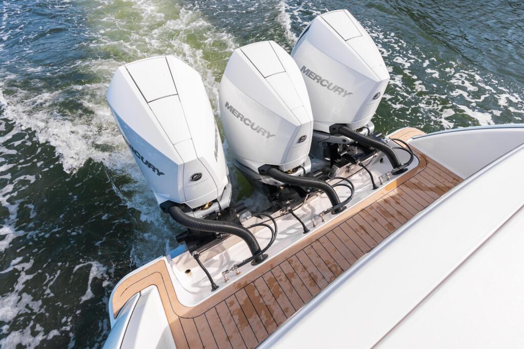 Twin Mercury outboard engines mounted on boat transom with teak swim platform and calm offshore waters