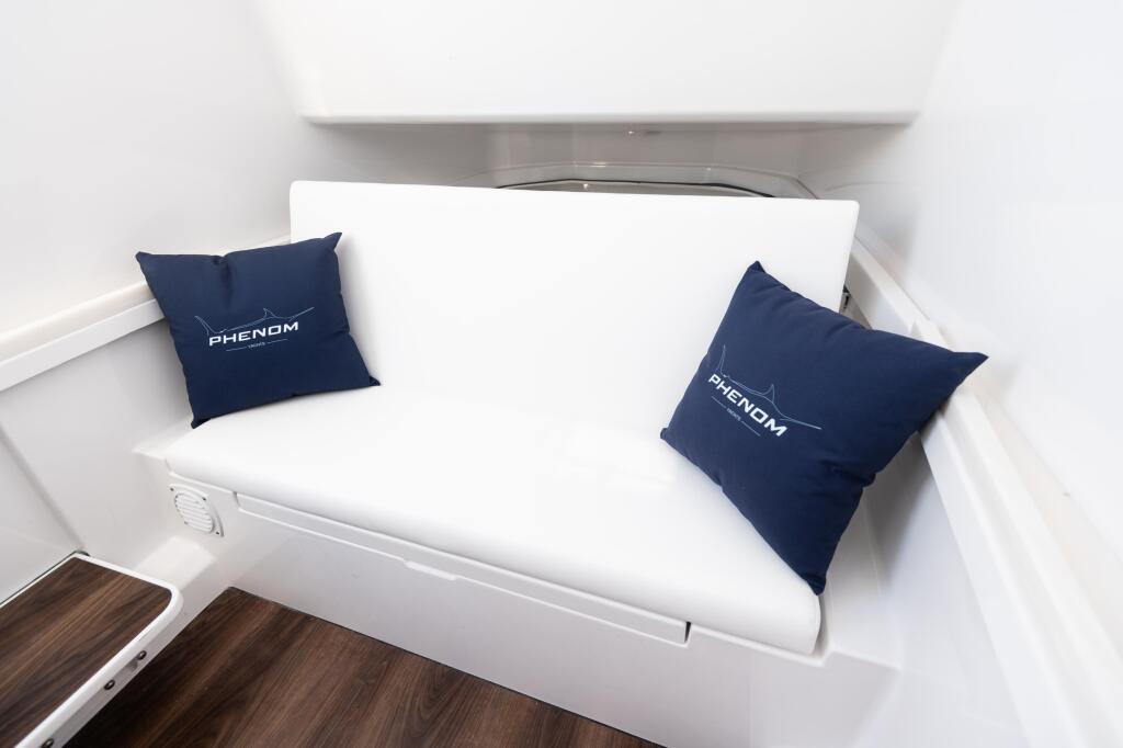 Phenom boat cabin with white cushioned bench seat and navy blue branded pillows