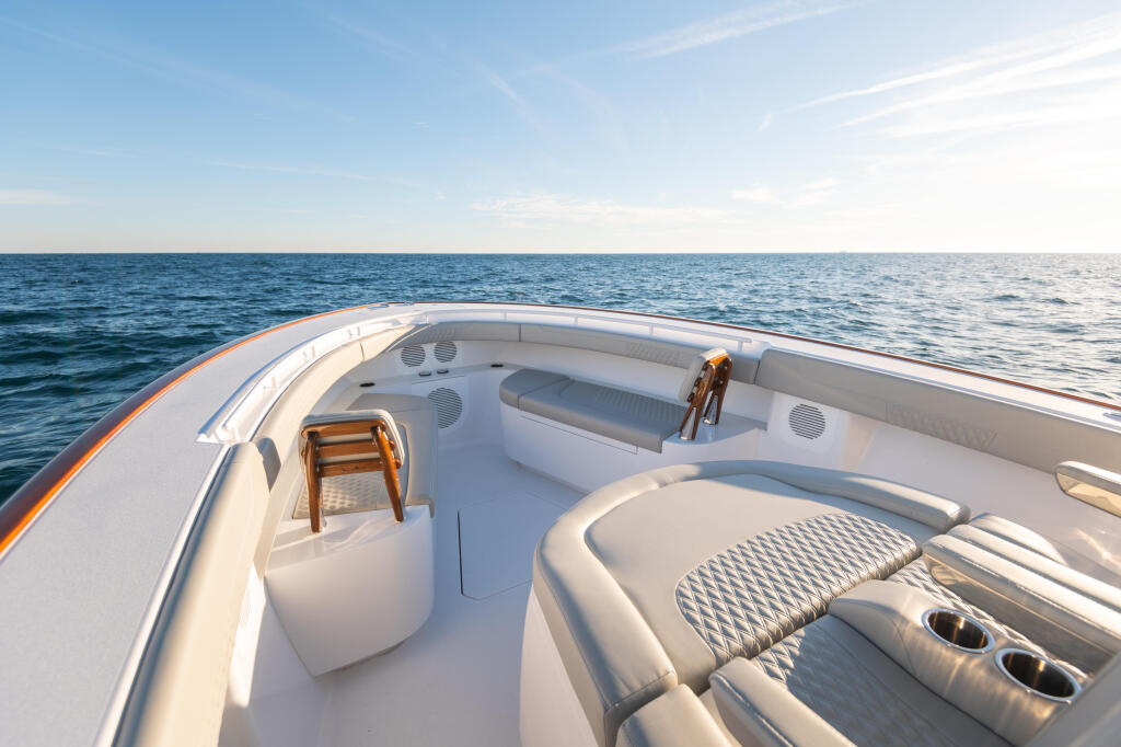 Spacious bow seating area with plush lounges and teak accents overlooking calm offshore waters