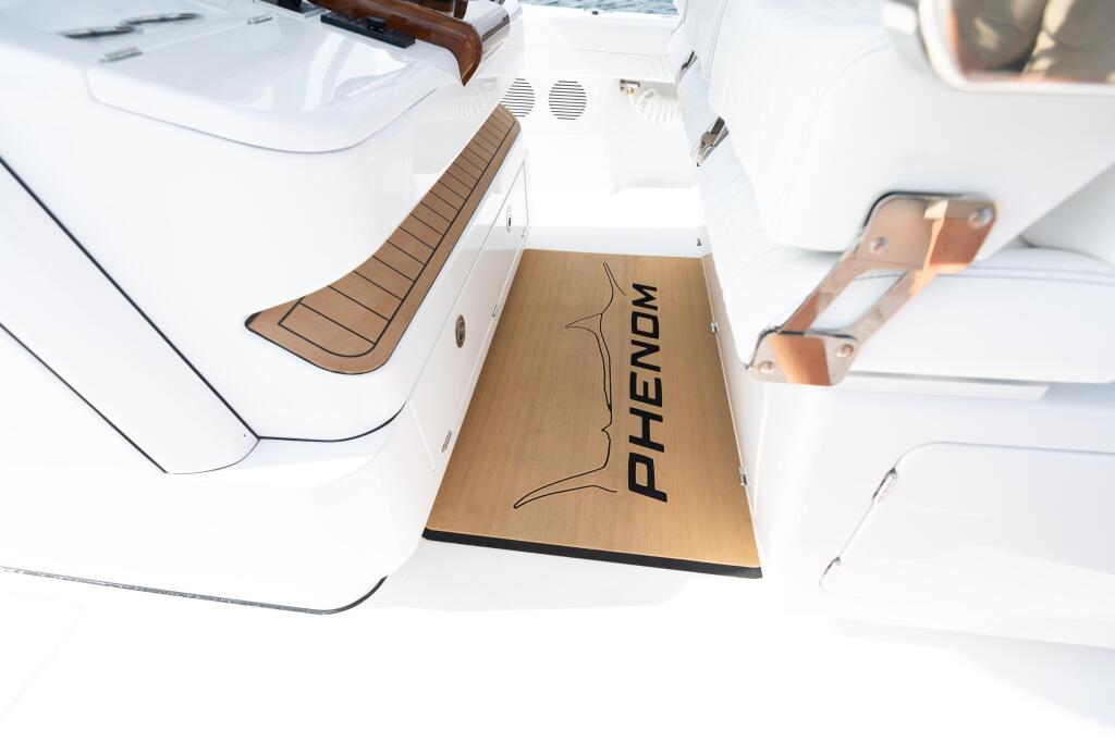 Overhead view of Phenom boat's white hull with teak wood leaning post and copper cleats