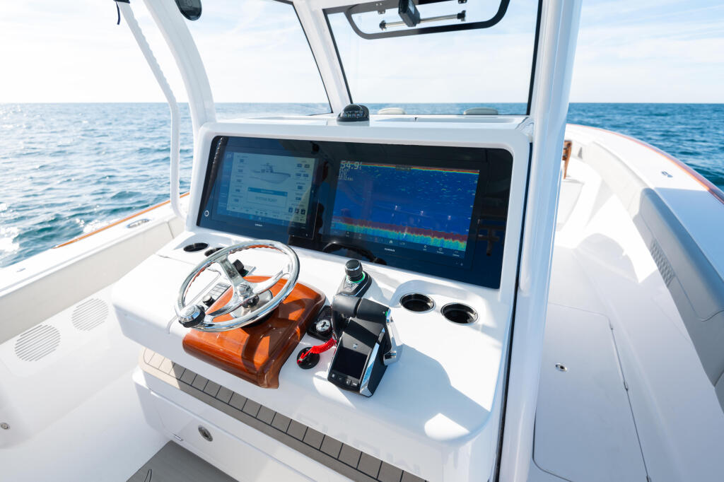 Helm station with dual Garmin chartplotters and orange-trimmed steering wheel overlooking open ocean