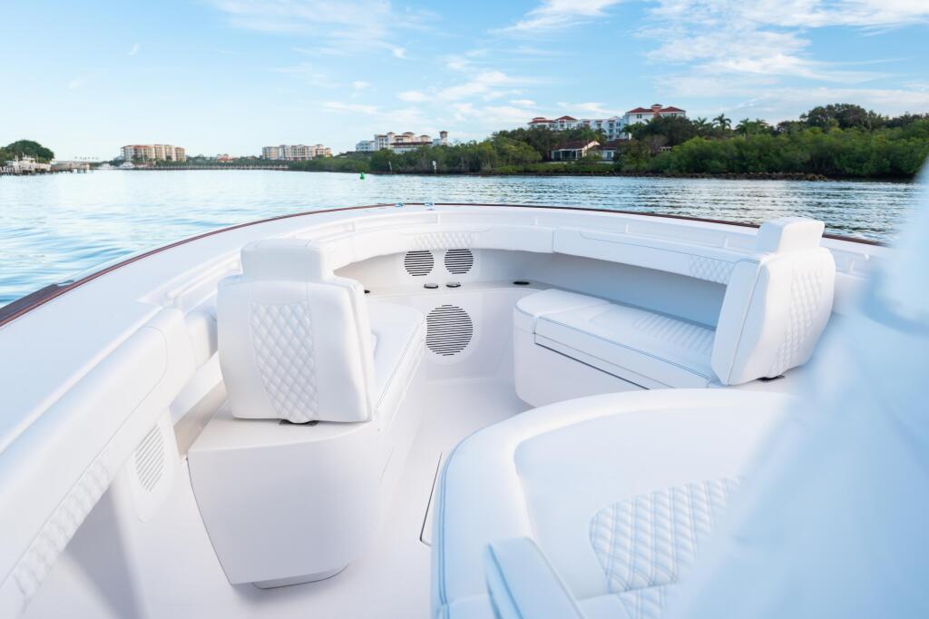 Spacious white bow seating with quilted backrests and built-in speakers overlooking a waterfront community