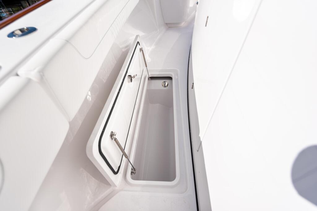 Open white in-deck storage box with stainless steel handles on boat gunwale