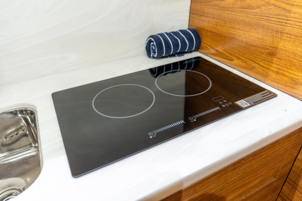 Modern induction cooktop with two burners integrated into galley countertop with wood cabinetry