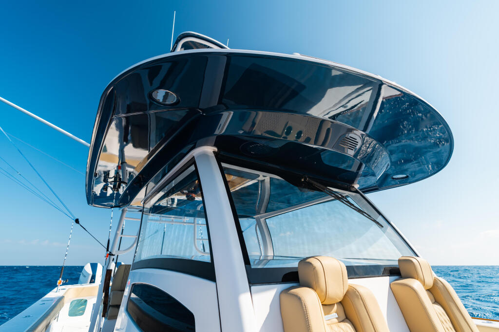 Hard-top structure with D-tubing overhead on a center console boat with tan seating and open ocean backdrop