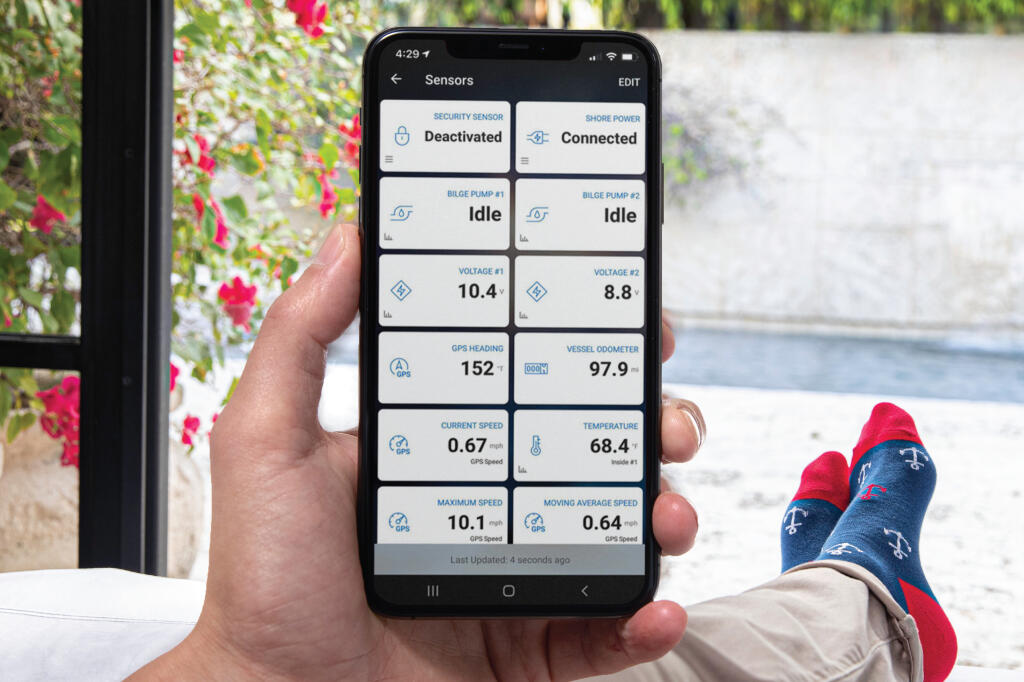 Smartphone displaying boat monitoring system with sensor data including voltage, GPS, speed, and temperature readings near water