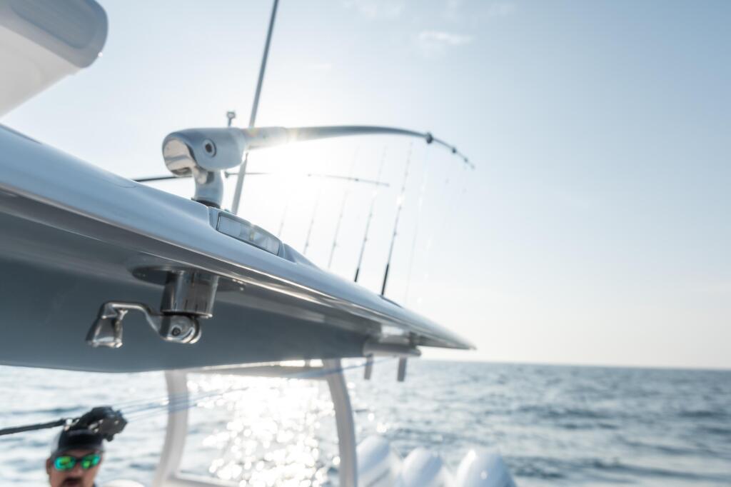 Close-up of boat's antenna and outrigger arm against open ocean and blue sky