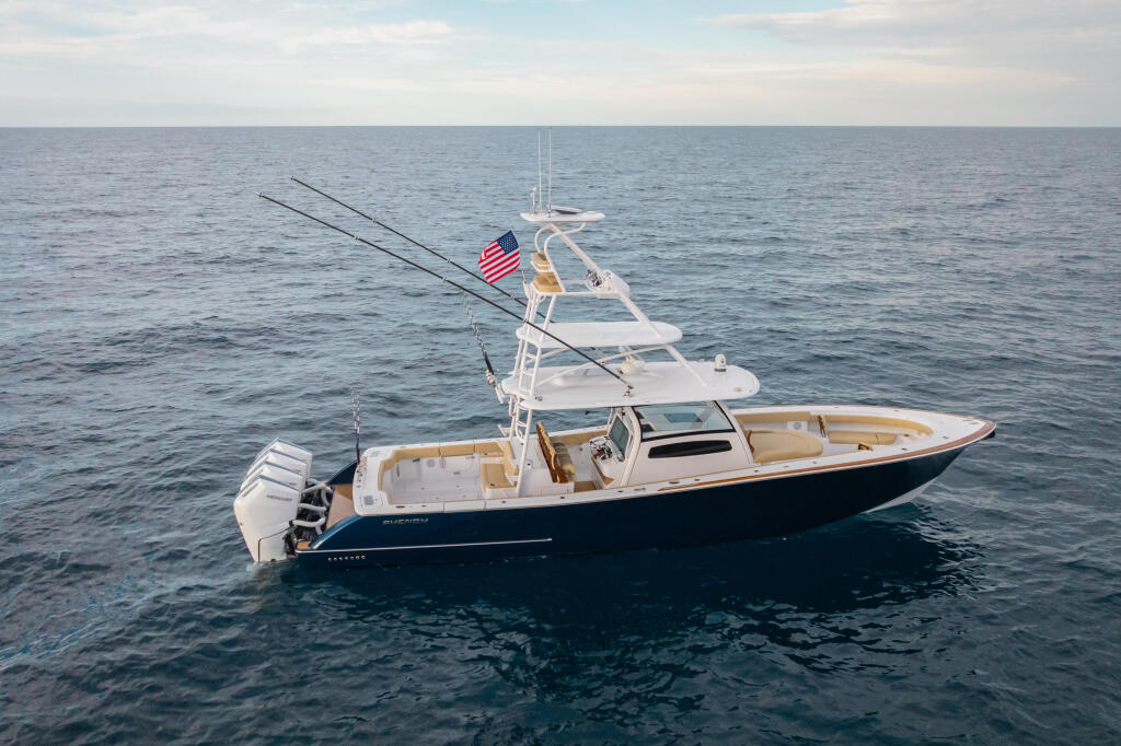 Offshore fishing boat anchored in calm blue water with outrigger poles extended and American flag flying