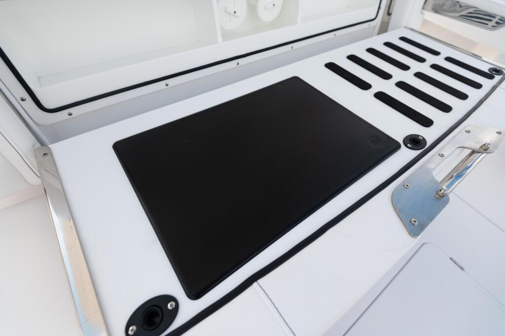 Overhead view of boat's cutting prep area with black cutting surface, rod holders, and stainless steel hardware