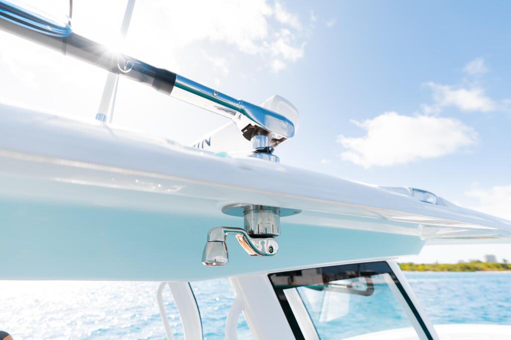Stainless steel outrigger and fishing electronics mounted on boat helm with turquoise offshore waters visible