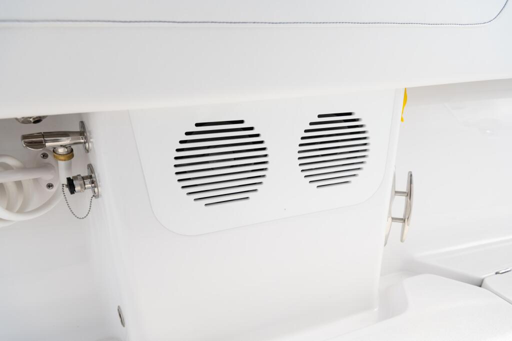 Dual black speaker grilles mounted on white hardtop interior with helm controls and hardware visible