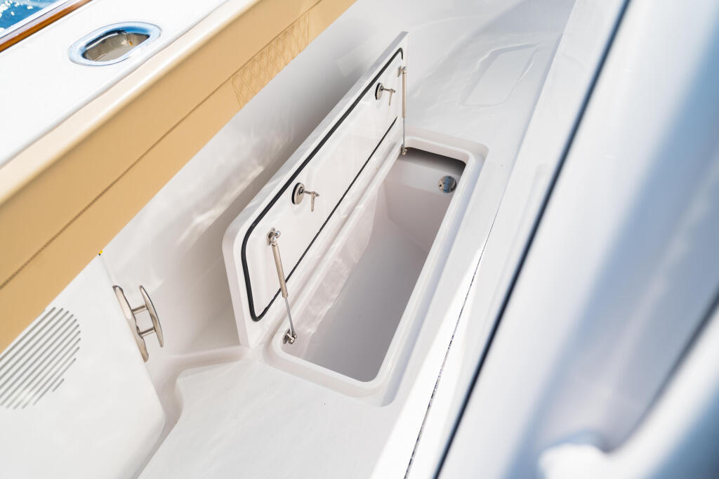 Open in-deck storage box with stainless steel handles and latch hardware on white boat gunwale