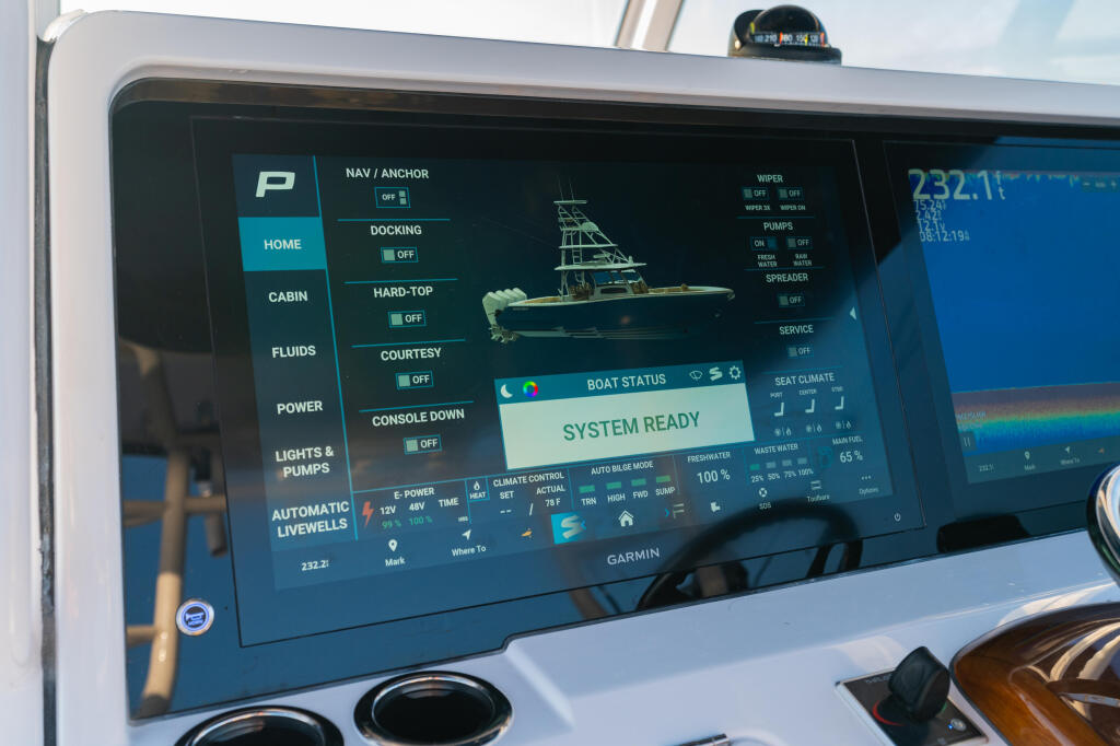 Garmin touchscreen display showing system status and boat control menus including navigation, docking, and livewell functions