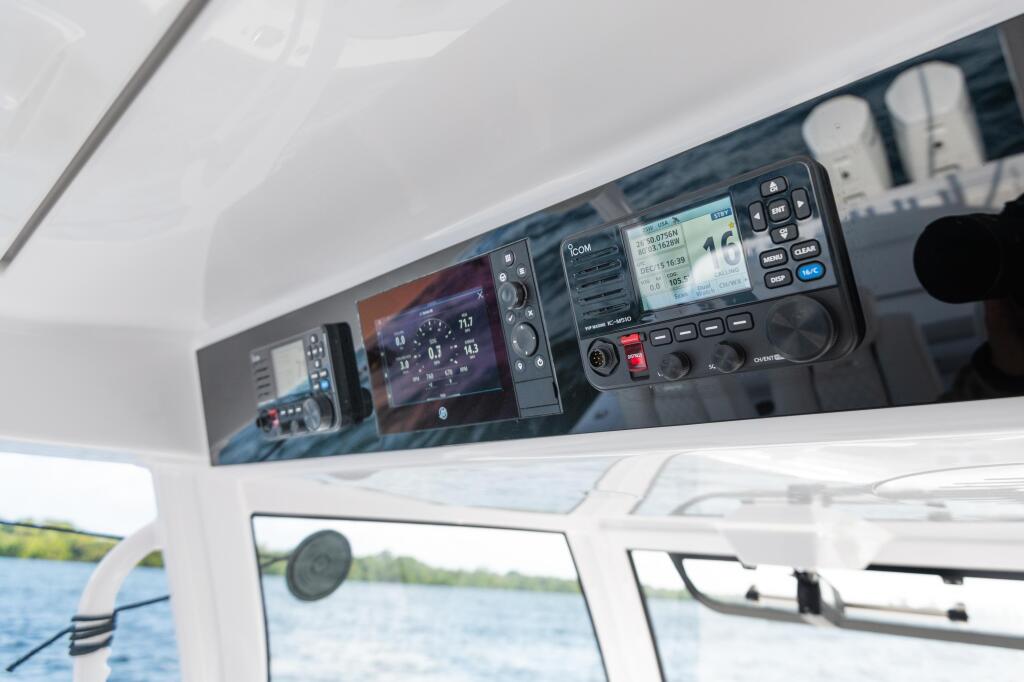 Marine electronics and VHF radio equipment mounted in boat helm console with water visible through windshield