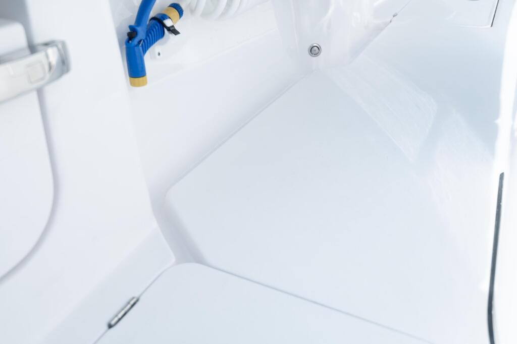 Overhead view of a bright white boat cockpit with a blue and tan fishing reel mounted on the side