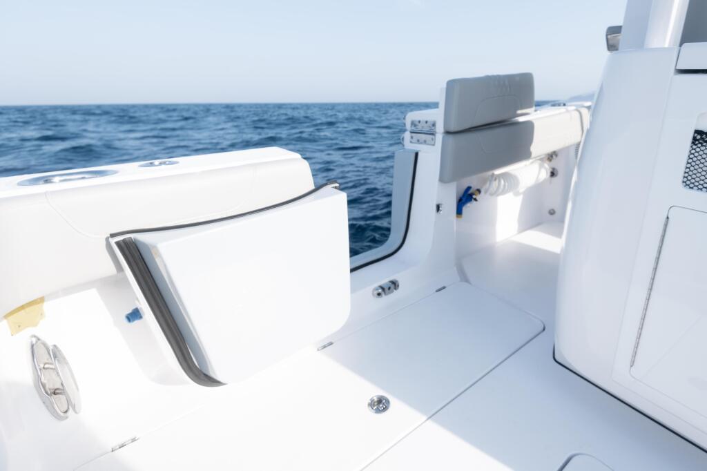 Clean white boat cockpit with gray seating and side entry door overlooking calm blue ocean