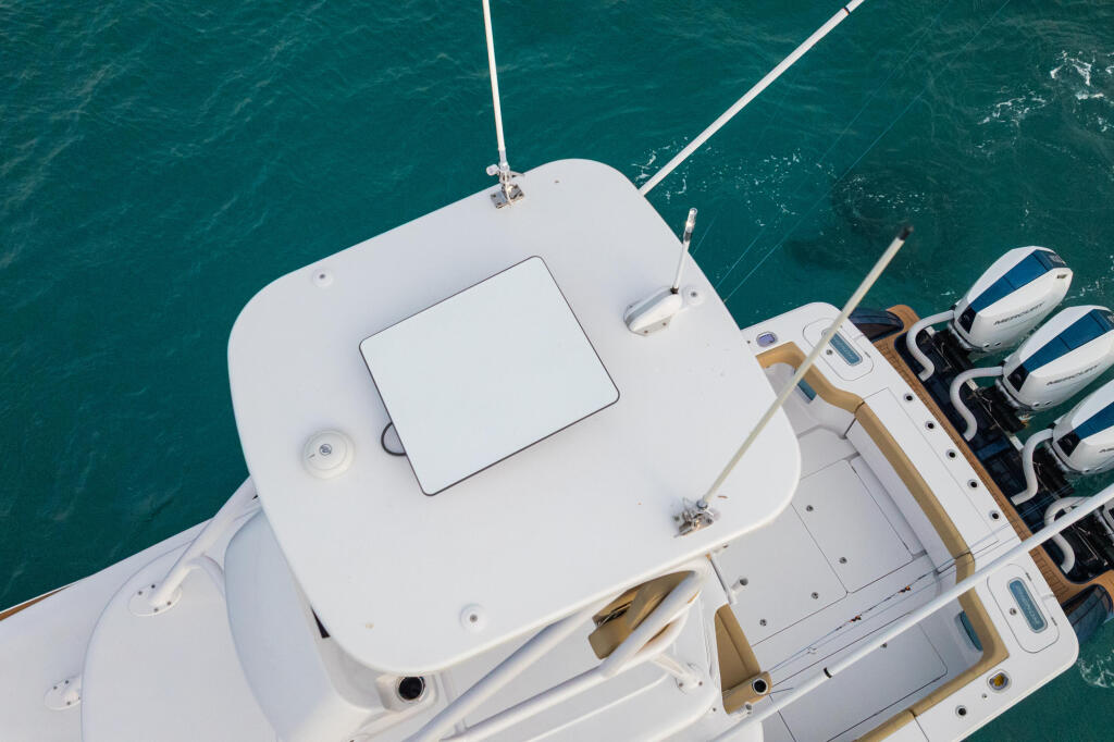 Aerial view of a white sport fishing boat with helm station, outriggers, and multiple engines moored in turquoise water