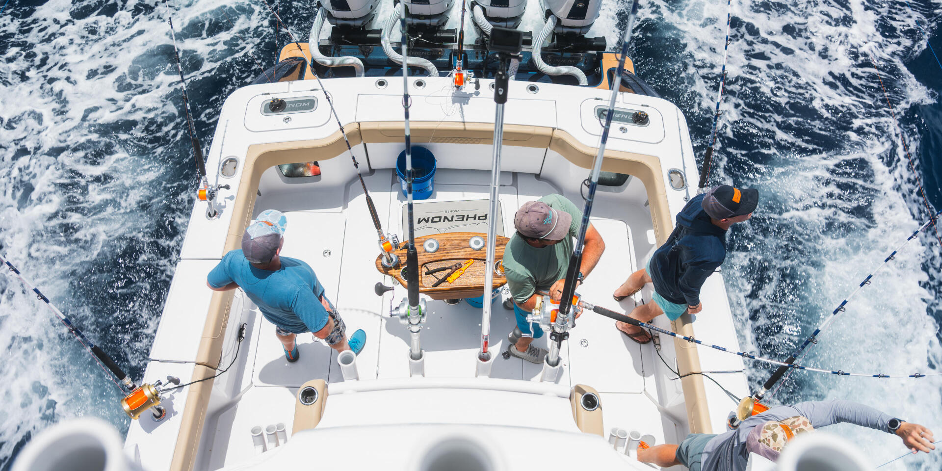 Aerial view of fishing boat with four anglers holding rods while cruising through offshore waters