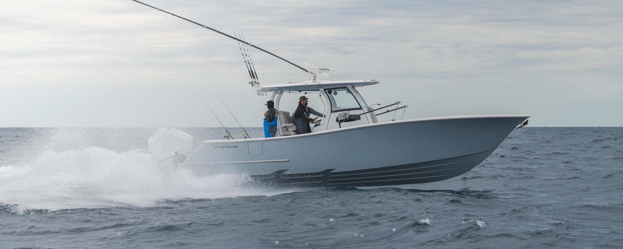 White center console boat with two people running through offshore waves under cloudy skies