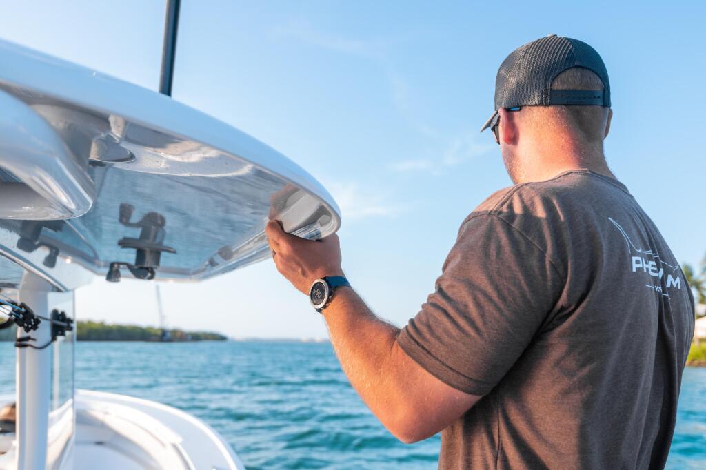 Boater adjusting the windshield while cruising on blue water