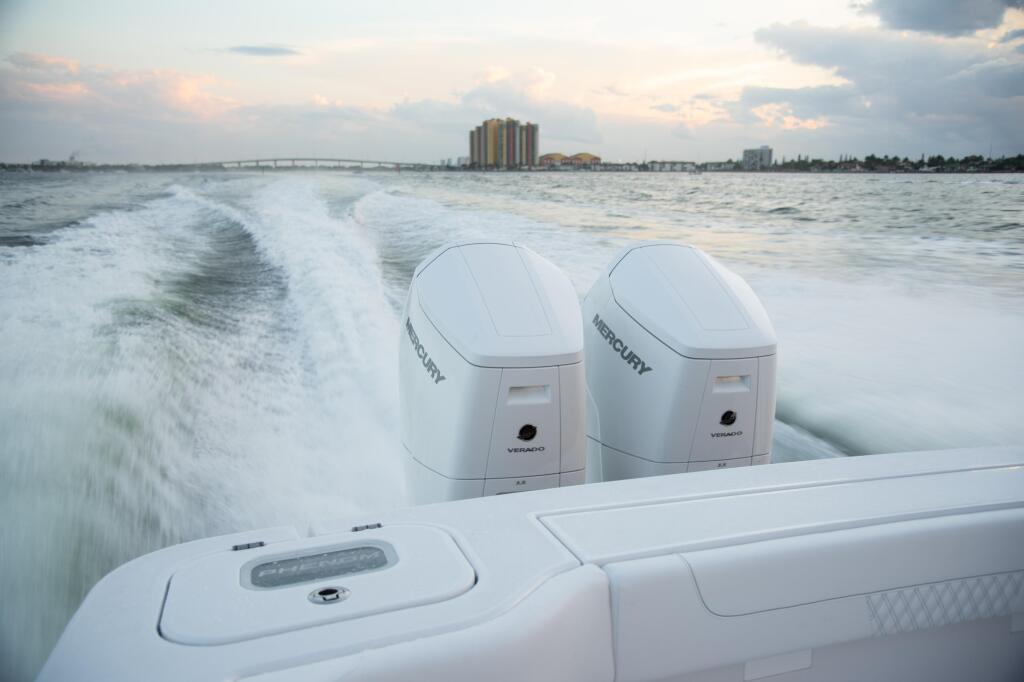 Twin Mercury Verado outboard engines mounted on boat running offshore with coastal cityscape in background
