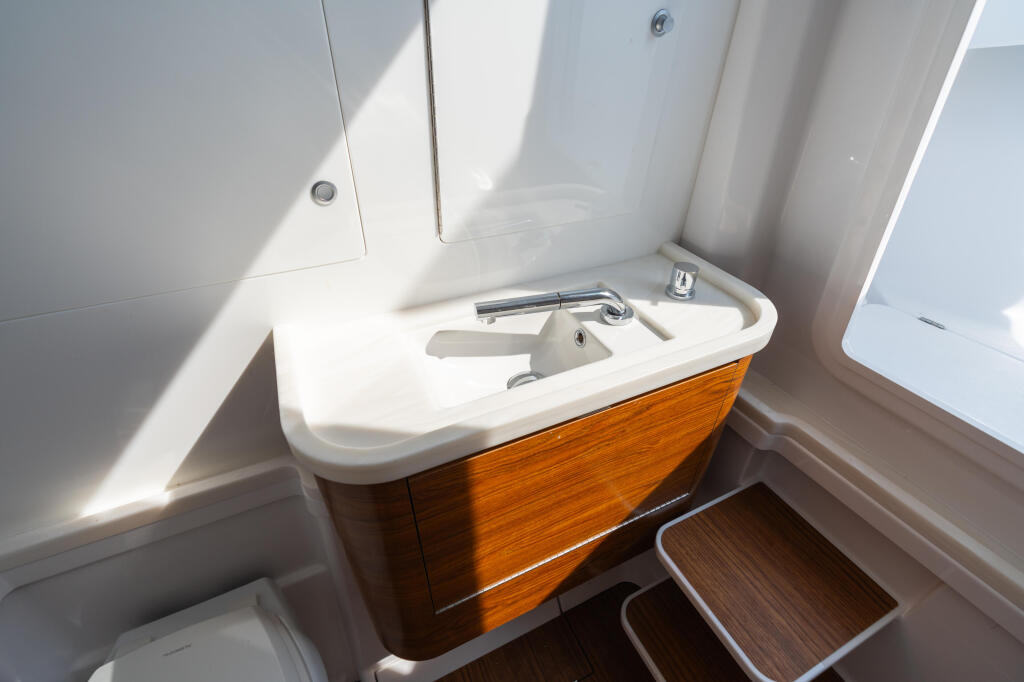 Cabin sink vanity with wood-grain cabinetry and chrome faucet in bright natural light